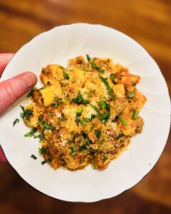 Homemade gnocchi with red sauce served in a shallow bowl topped with parmesan and basil